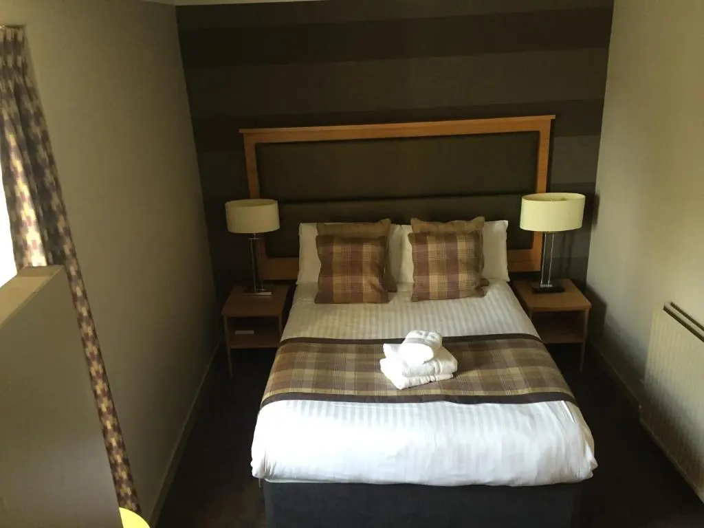 a hotel room with a bed with two lamps at Buchan Hotel in Ellon