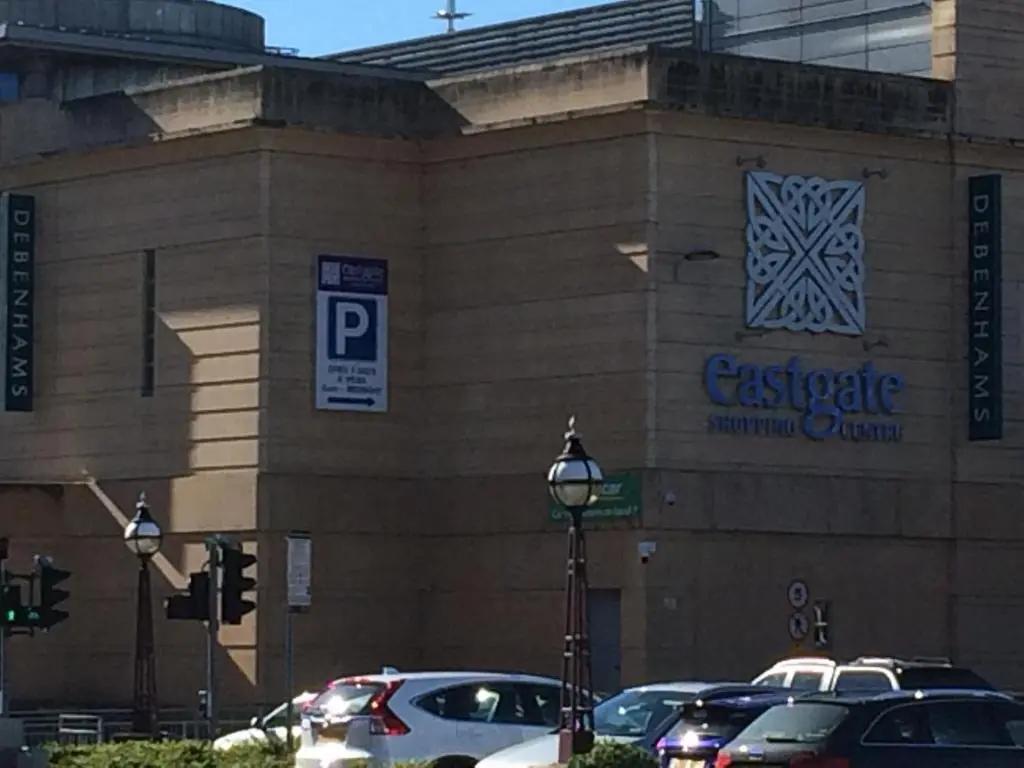 a parking lot with cars parked in front of a building at Eastgate Apartment in Inverness