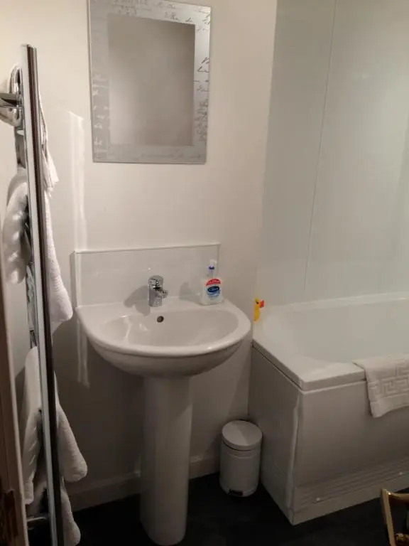 a white bathroom with a sink and a toilet at Eastgate Apartment in Inverness