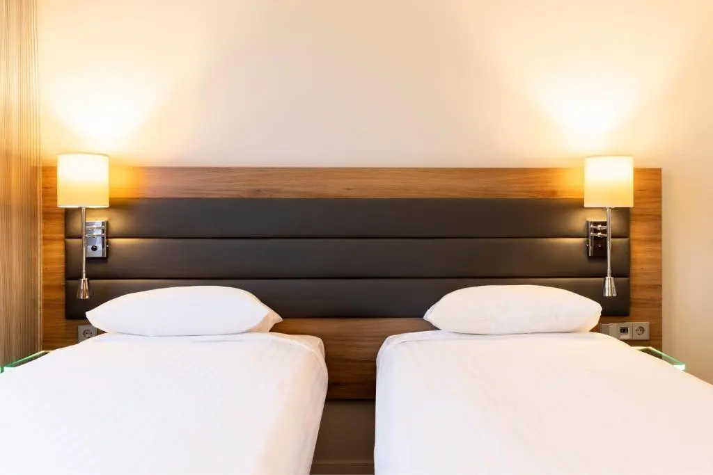 two beds in a hotel room with white sheets at Moxy Aberdeen Airport in Dyce