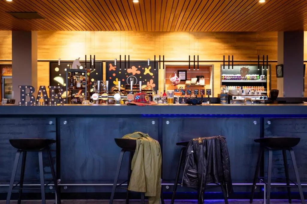 a blue bar with stools in a restaurant at Moxy Aberdeen Airport in Dyce