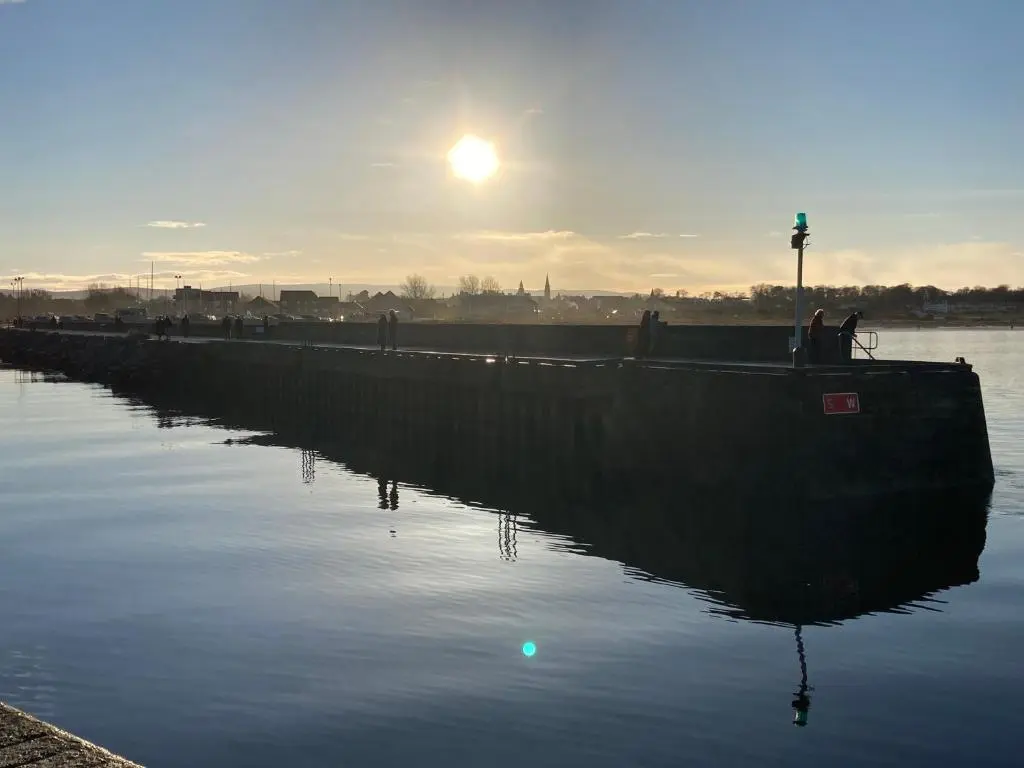 a boat in the water with the sun in the background at Luxury Apartment at Barron House in Nairn