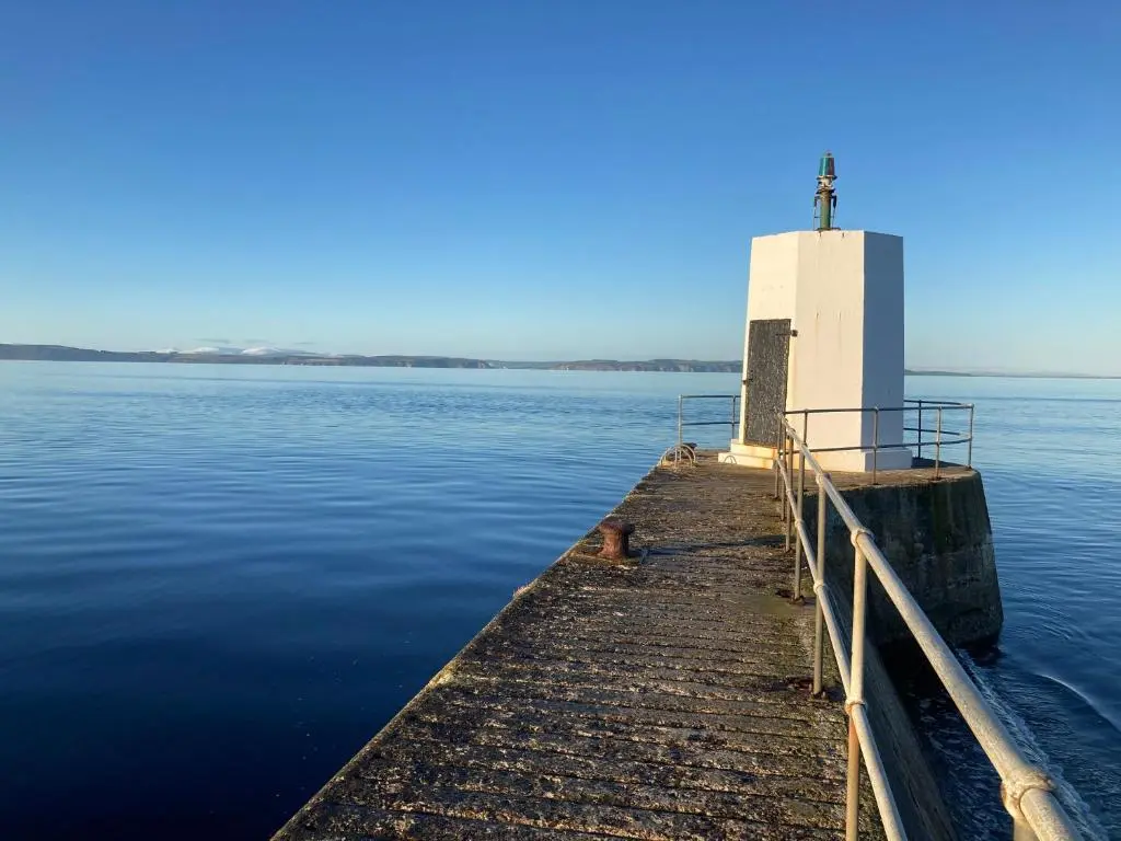 a lighthouse on the end of a pier in the water at Luxury Apartment at Barron House in Nairn
