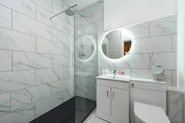 a white bathroom with a sink and a shower at Strathardle Lodge in Kirkmichael