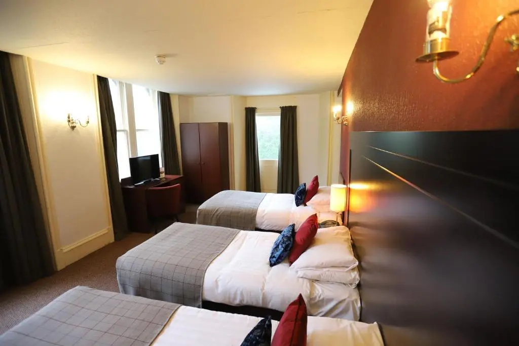 a hotel room with three beds and a television at Ben Wyvis Hotel in Strathpeffer