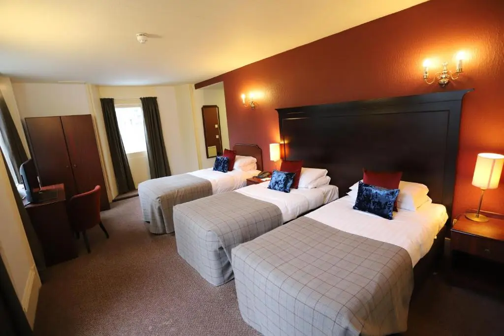 a hotel room with three beds in a room at Ben Wyvis Hotel in Strathpeffer