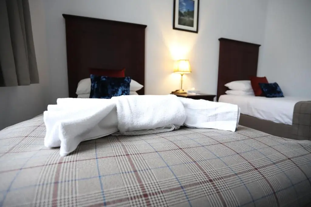 a hotel room with two beds with white towels on the bed at Ben Wyvis Hotel in Strathpeffer