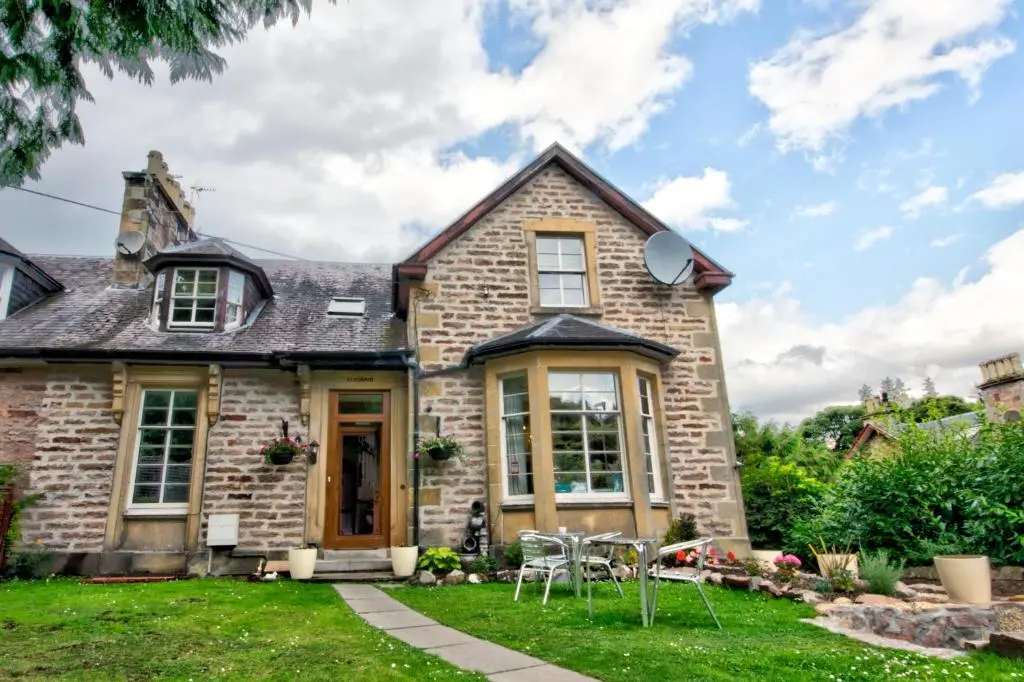 a brick house with a table and chairs in the yard at Glasdair in Inverness