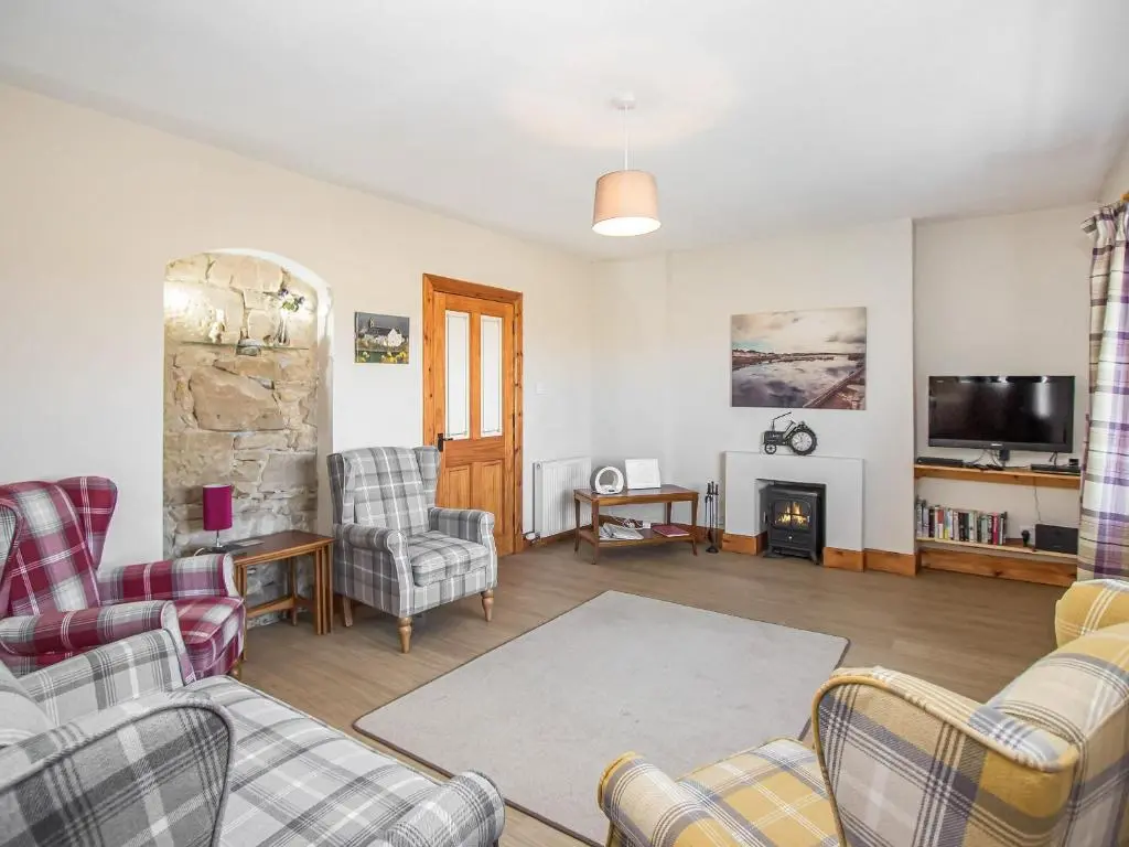 a living room with chairs and a fireplace at The Paddock in Portmahomack