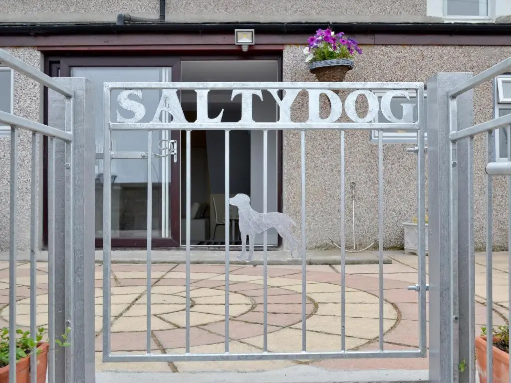 a metal gate with a white dog on it at Salty Dog in Findochty