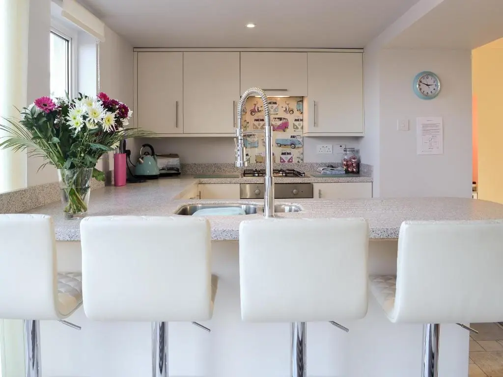 a kitchen with white cabinets and a sink with white chairs at Salty Dog in Findochty