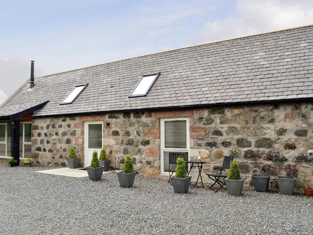 a stone house with potted plants in front of it at Longcroft Dairy in Oyne