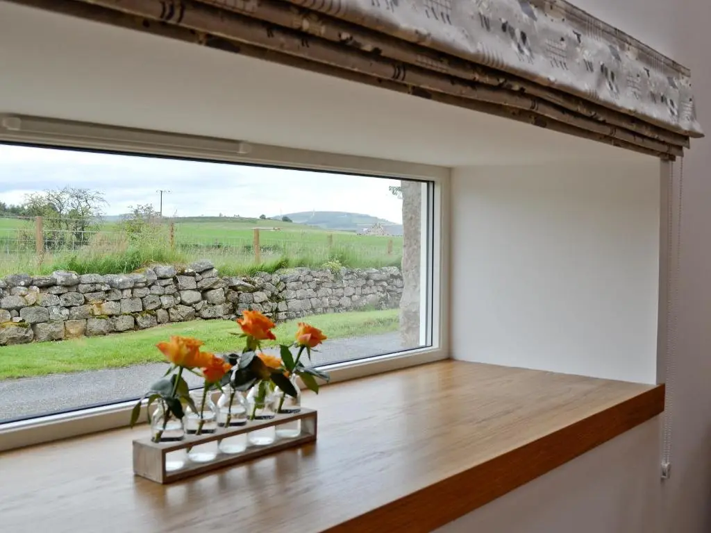 a window with orange flowers in vases on a table at Longcroft Dairy in Oyne