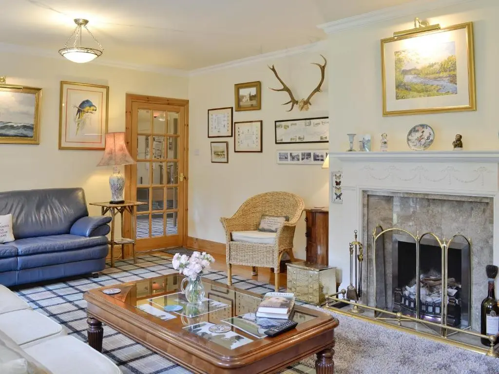a living room with a fireplace and a blue couch at Little Blackhall Lodge in Banchory