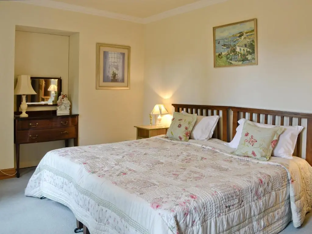 a bedroom with a large bed with a wooden headboard at Little Blackhall Lodge in Banchory
