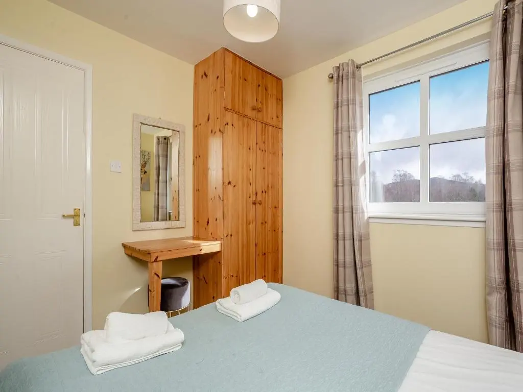 a bedroom with a blue bed and a window at Cairnie View in Aviemore