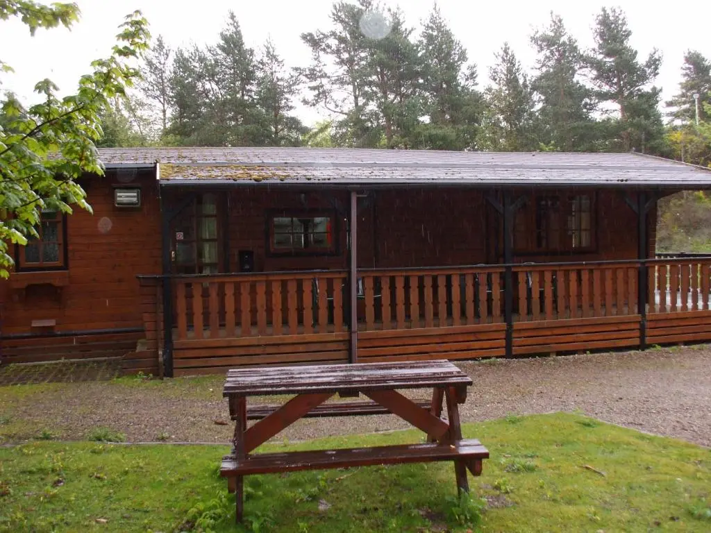 a wooden cabin with a picnic table in front of it at Lurchers Cabin Aviemore in Aviemore