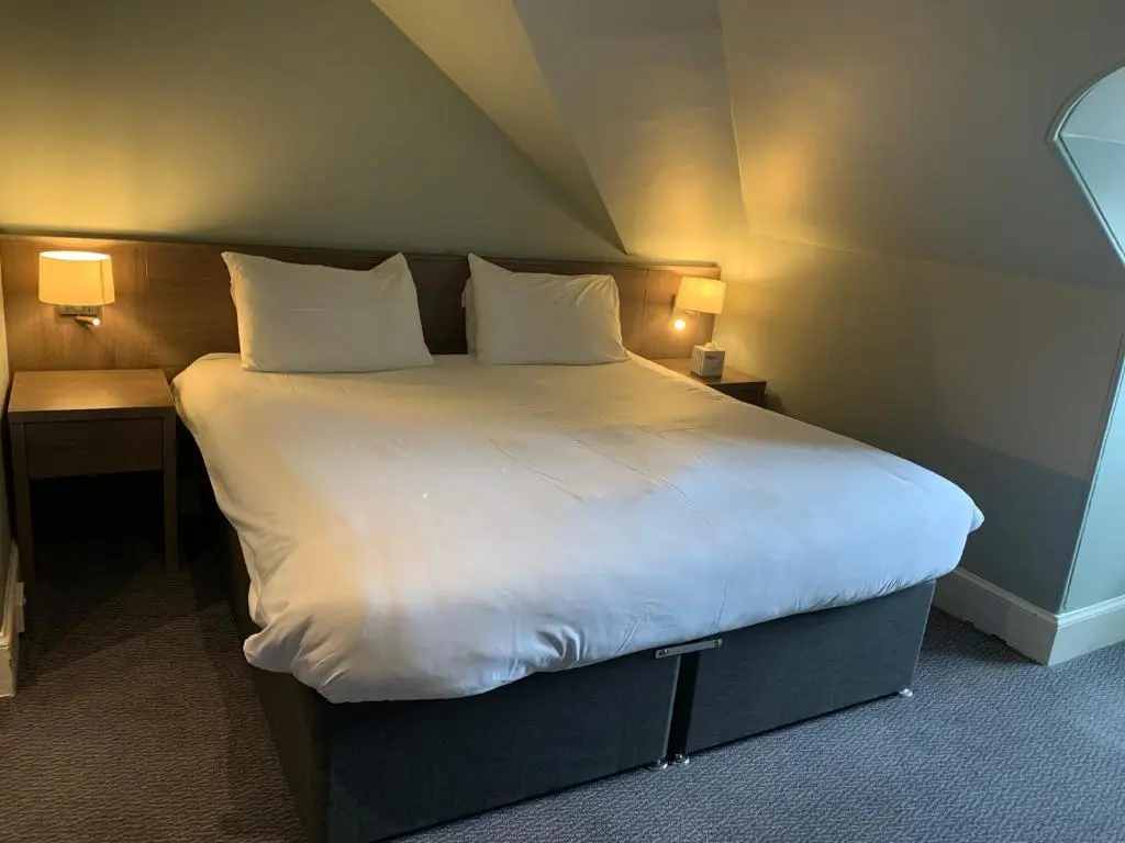 a large bed with white sheets and pillows in a room at The Royal Hotel Elgin in Elgin