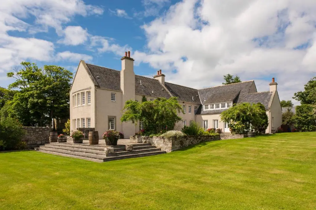 an exterior view of a large house with a large yard at The Glenmorangie House in Tain