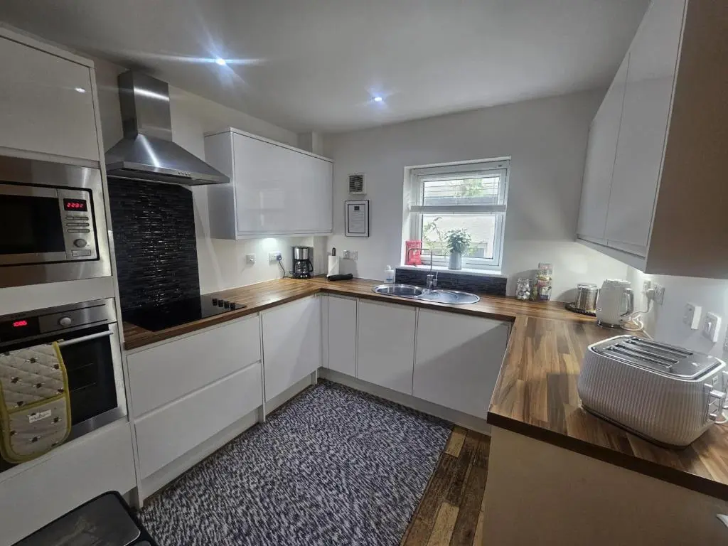a kitchen with white cabinets and a window at LANGLEY APARTMENT free parking outside between 6 pm and 8 am Secure parking 2 min walk Ideal for TRADES AND TOURISTS WANTING GREAT LOCATION in Inverness