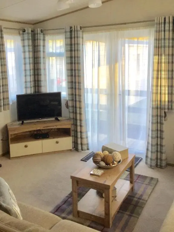 a living room with a television and a coffee table at Dunroamin Lodge in Aviemore