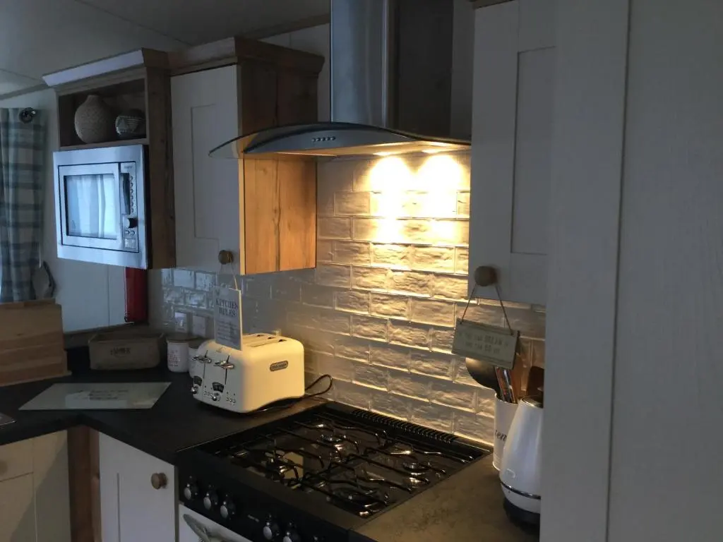 a kitchen with a stove top oven with a light at Dunroamin Lodge in Aviemore