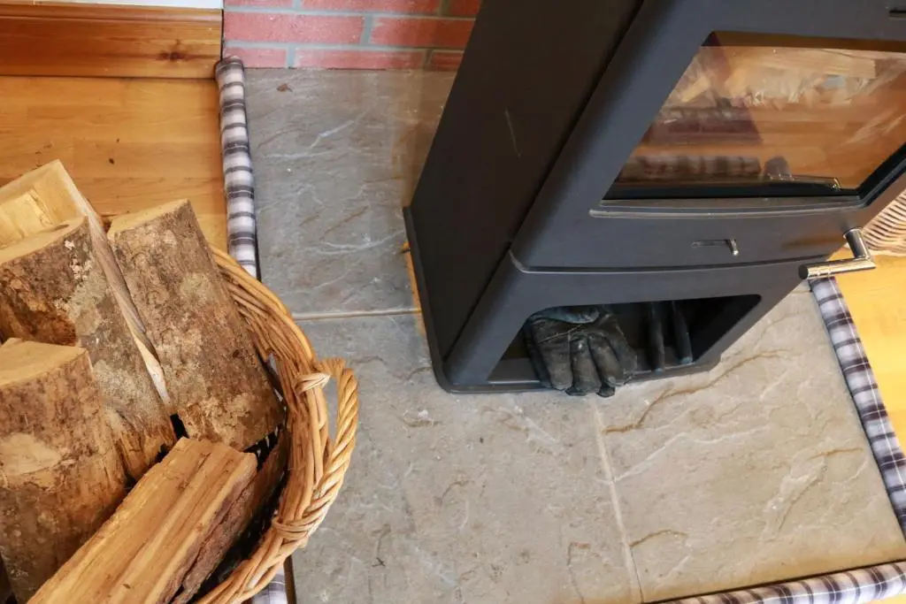 a fireplace with a tv and a basket of wood at Tanar View in Aboyne
