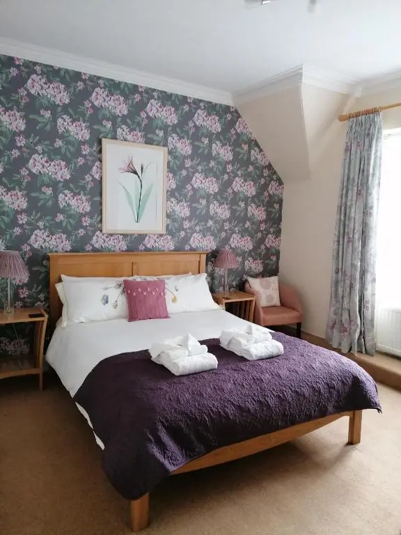 a bedroom with a large bed with a purple blanket at St Ann\u2019s Guest House in Inverness