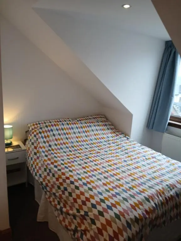a bed with a colorful bedspread in a room at Holiday House Kinveachy in Aviemore
