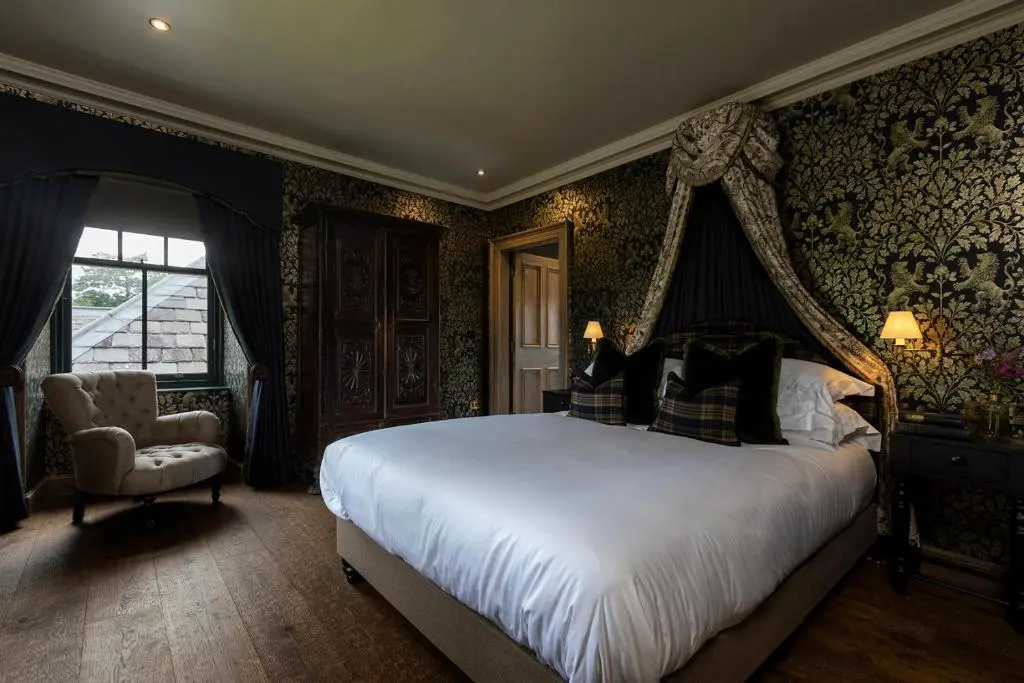 a bedroom with a large bed and a chair at Kildrummy Inn in Kildrummy