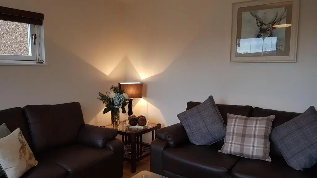 a living room with two leather couches and a table at The Little House by the Ness in Inverness