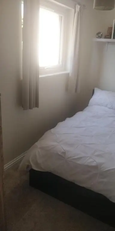 a bedroom with a white bed with a window at The Little House by the Ness in Inverness