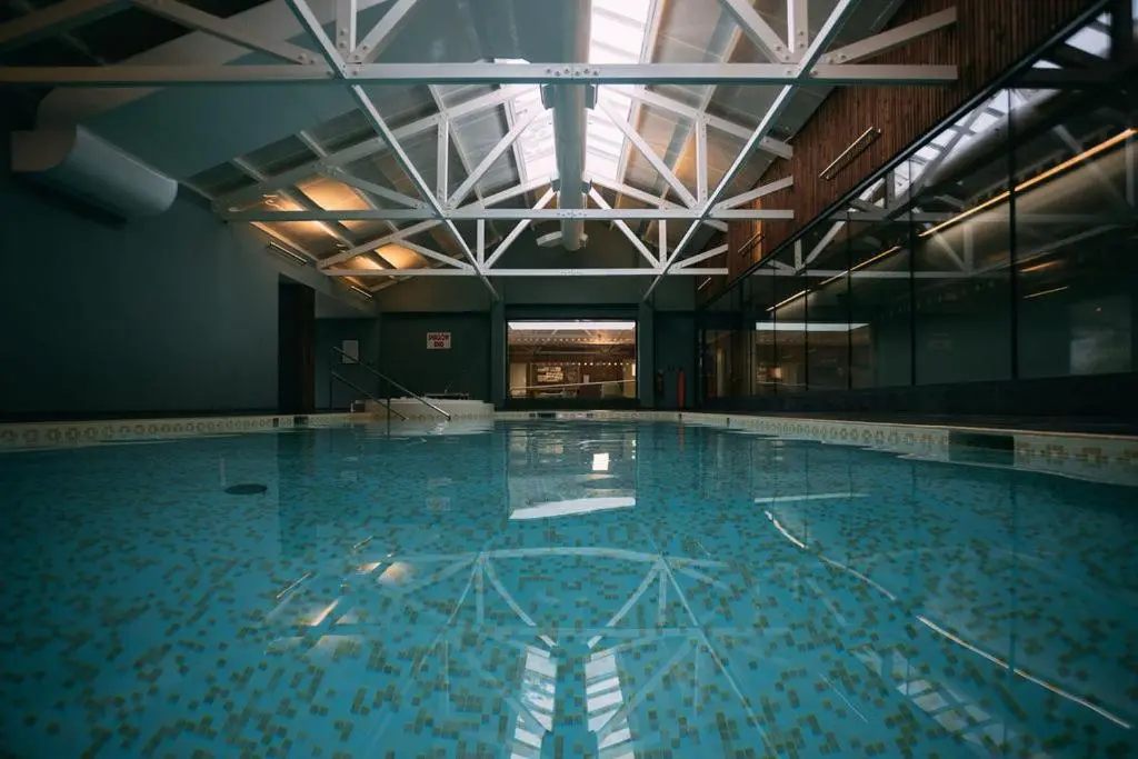 a swimming pool with blue water in a building at Douneside House in Tarland