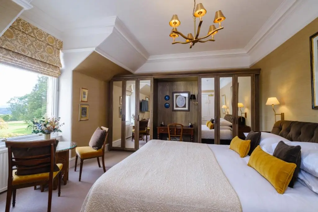 a large bedroom with a large bed and a desk at Douneside House in Tarland