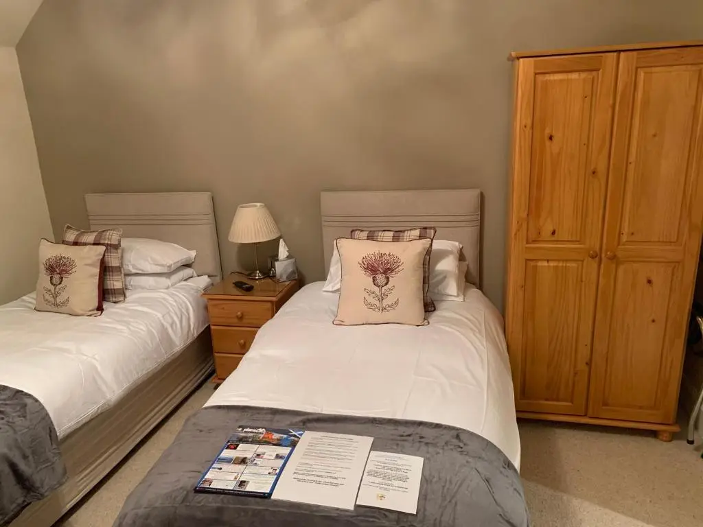 a bedroom with two beds and a wooden cabinet at Drumdale Bed and Breakfast in Inverness