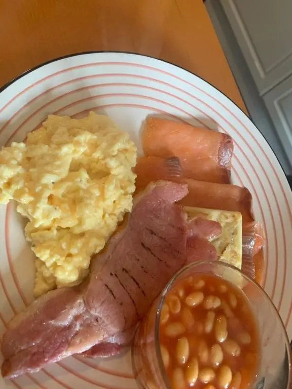 a plate of breakfast food with eggs ham and beans at Drumdale Bed and Breakfast in Inverness