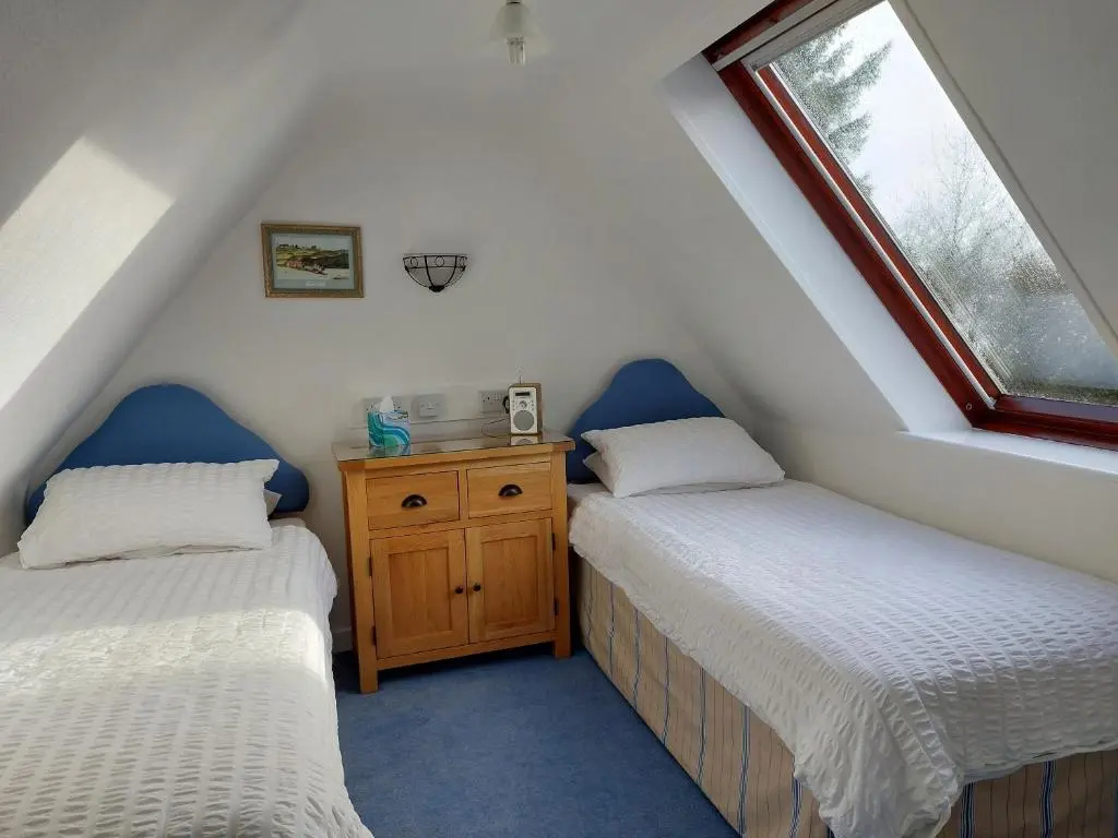 a attic room with two beds and a window at Chapelhill Croft in Keith