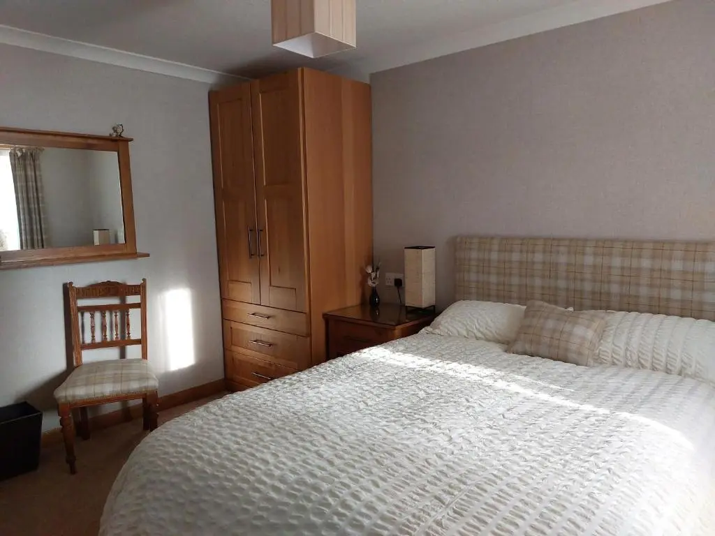 a bedroom with a bed and a chair and a mirror at Chapelhill Croft in Keith