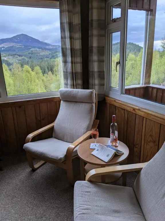 a room with two chairs and a table and windows at Faichemard Farm Chalets in Invergarry