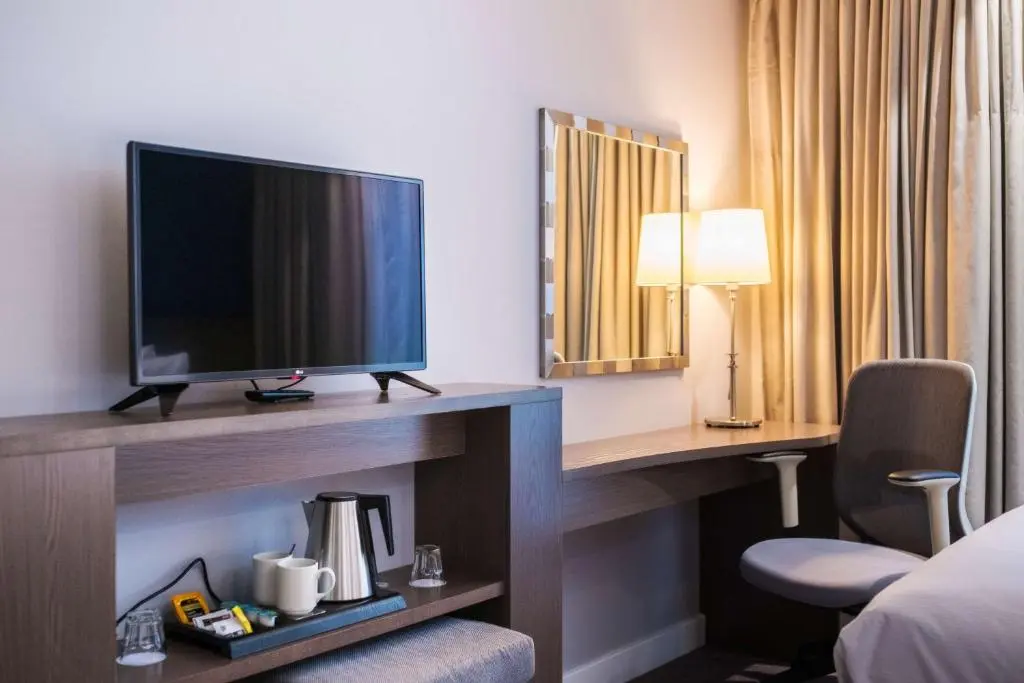 a hotel room with a television and a desk with a chair at Hampton By Hilton Aberdeen Airport in Dyce