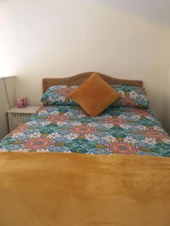a bed with a floral bedspread and a pillow on it at Bankhead Accommodation Aberdeenshire in Gamrie