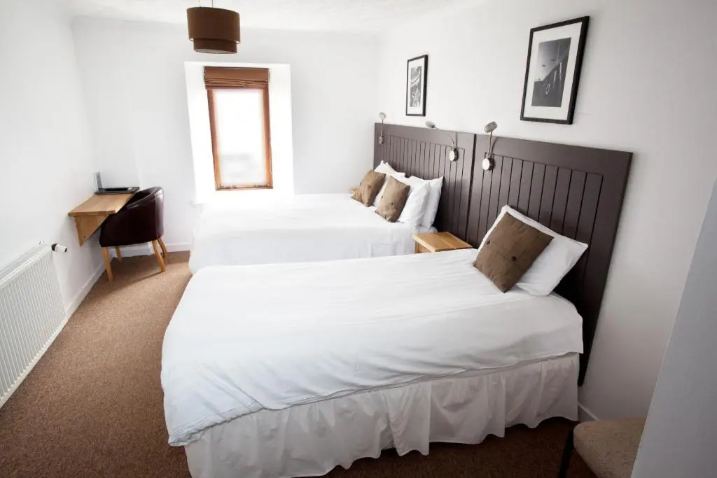 two beds in a hotel room with white sheets at The Arch Inn in Ullapool