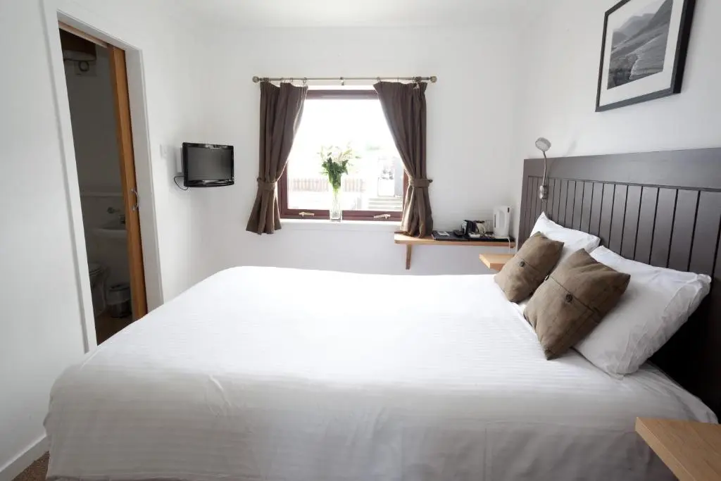 a bedroom with a large white bed with a window at The Arch Inn in Ullapool