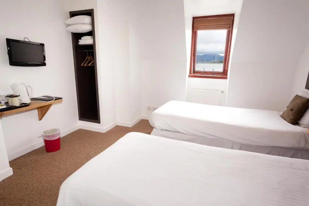 a hotel room with two beds and a television at The Arch Inn in Ullapool