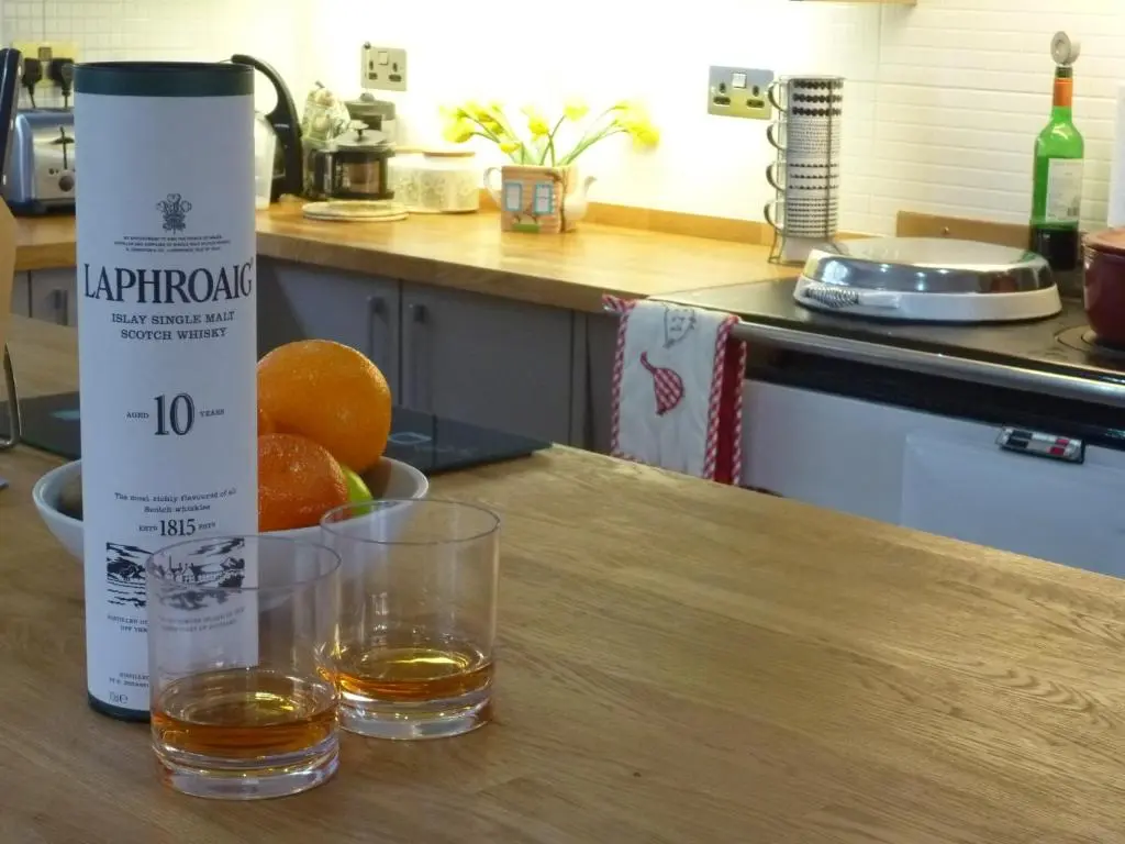 two glasses of alcohol sitting on a wooden table at Camusmore House in Aviemore