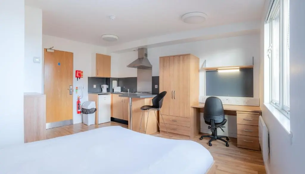 a bedroom with a bed and a desk and a kitchen at UHI Inverness - Campus Accommodation in Inverness