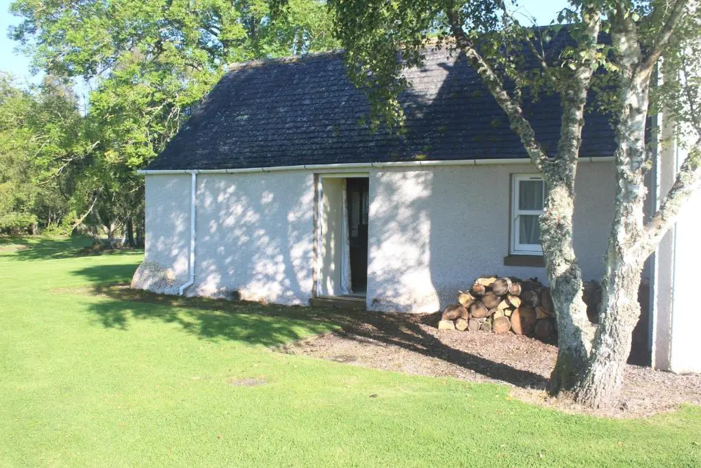 a white house with a tree in front of it at The Annex - Easter Arr in Auldearn