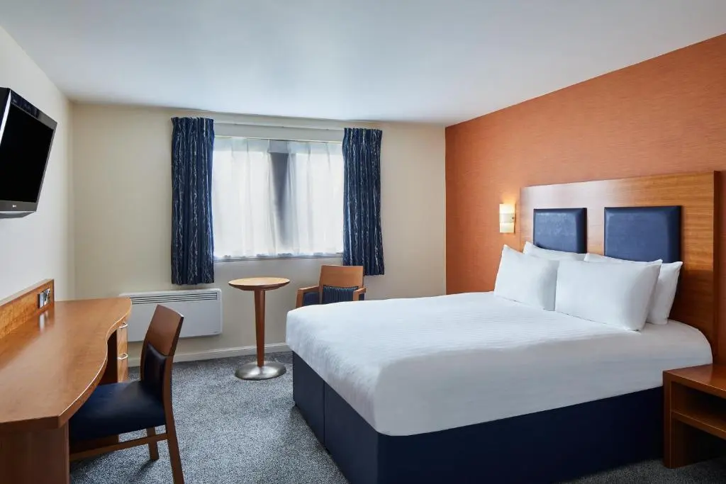 a hotel room with a large bed and a desk at Leonardo Inn Aberdeen Airport in Dyce