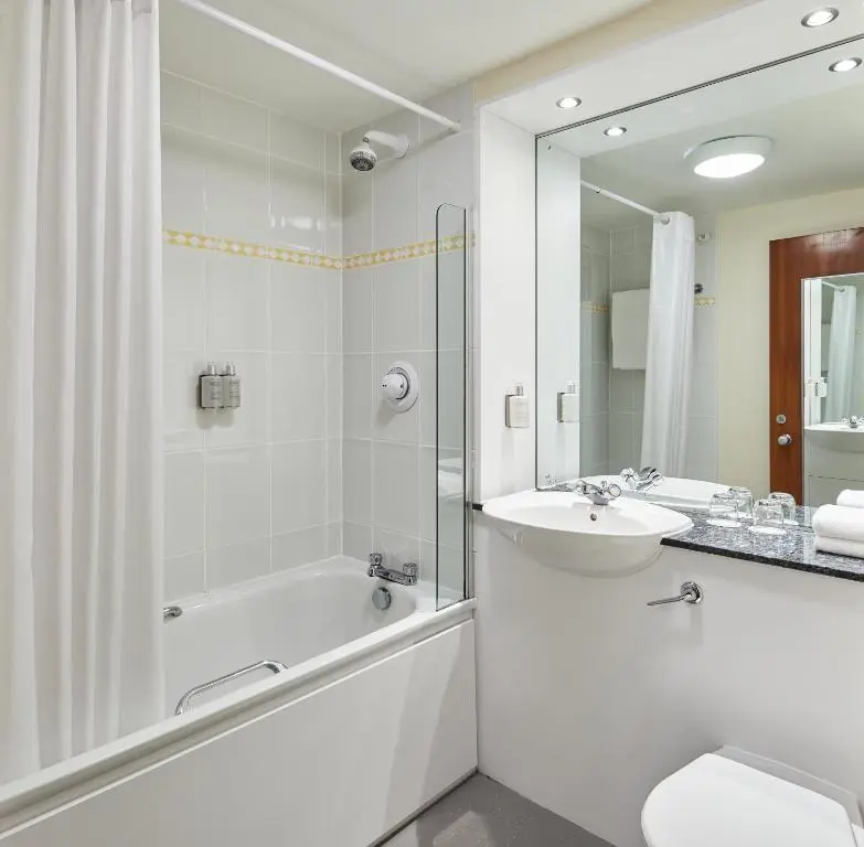 a white bathroom with a tub and a sink and a bath tubermott at Leonardo Inn Aberdeen Airport in Dyce