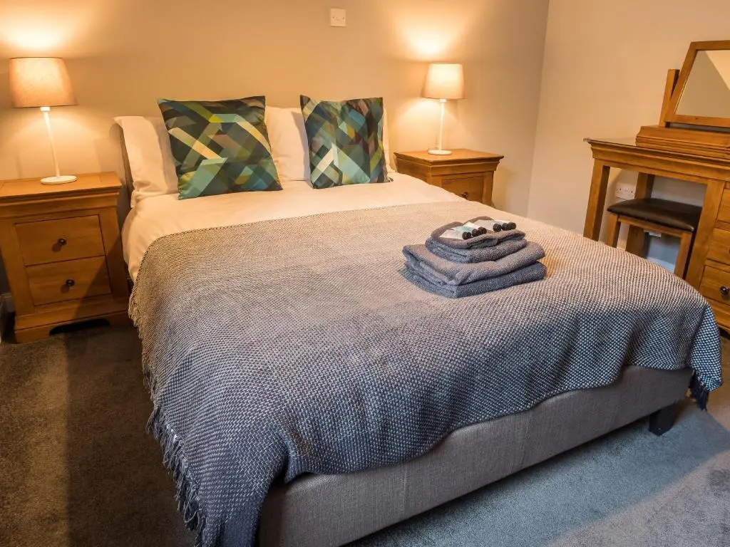 a bedroom with a bed with two night stands and two lamps at The Birches in Dingwall